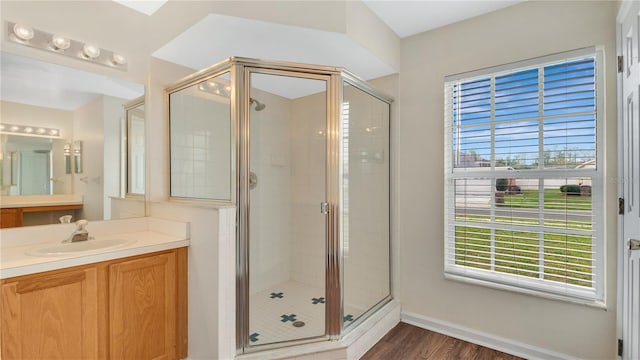 full bathroom featuring a stall shower, baseboards, wood finished floors, and vanity