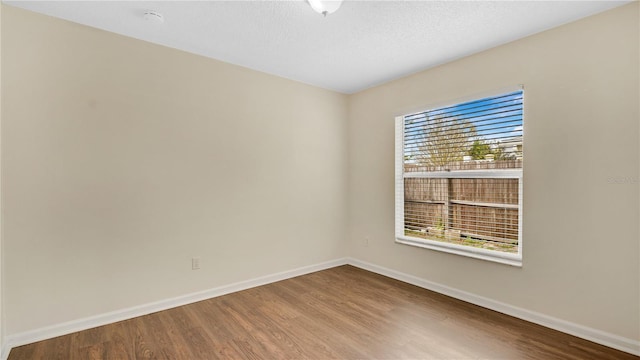 unfurnished room with baseboards and wood finished floors