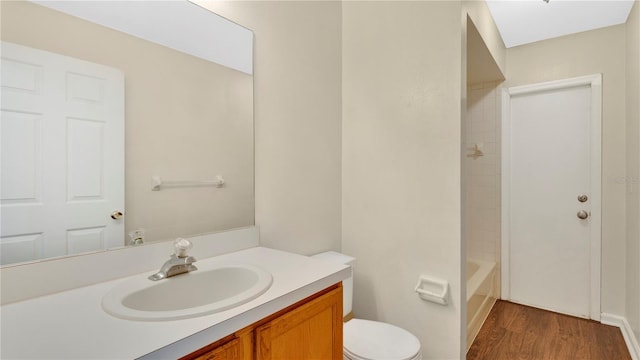 full bath with toilet, wood finished floors, and vanity