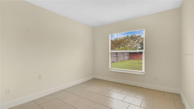 empty room featuring a healthy amount of sunlight, baseboards, and light tile patterned floors