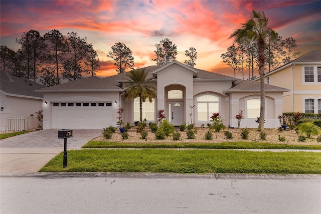 view of front of house with a garage, decorative driveway, and stucco siding