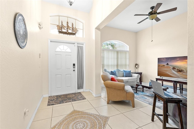 entryway featuring light tile patterned flooring, ceiling fan, and baseboards