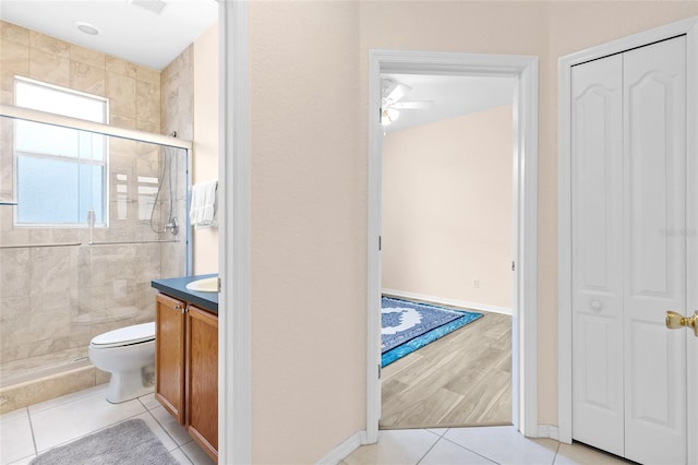 bathroom featuring toilet, a stall shower, tile patterned flooring, and vanity