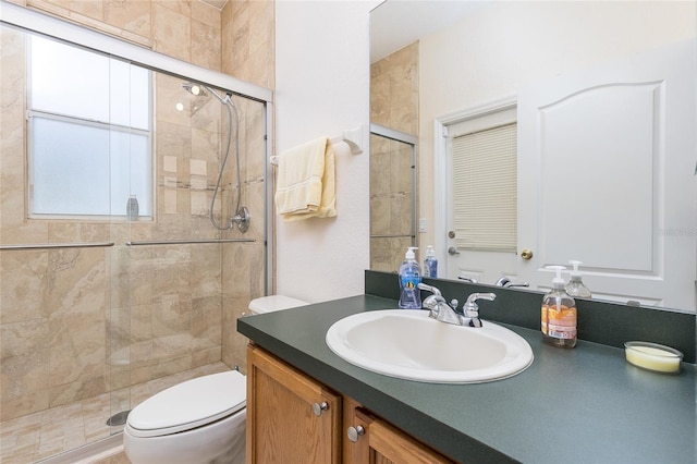 bathroom featuring toilet, a stall shower, and vanity