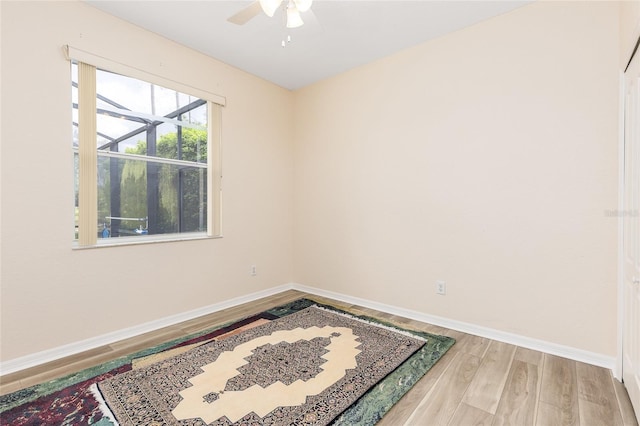 unfurnished room with a ceiling fan, light wood-style flooring, and baseboards