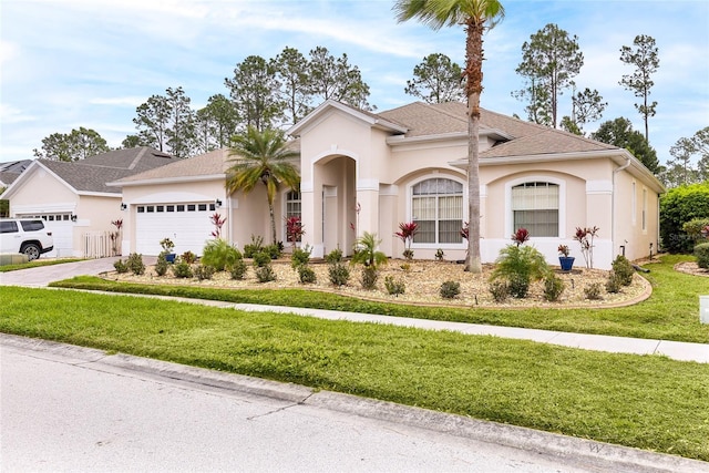 mediterranean / spanish home with a garage, a shingled roof, concrete driveway, stucco siding, and a front lawn