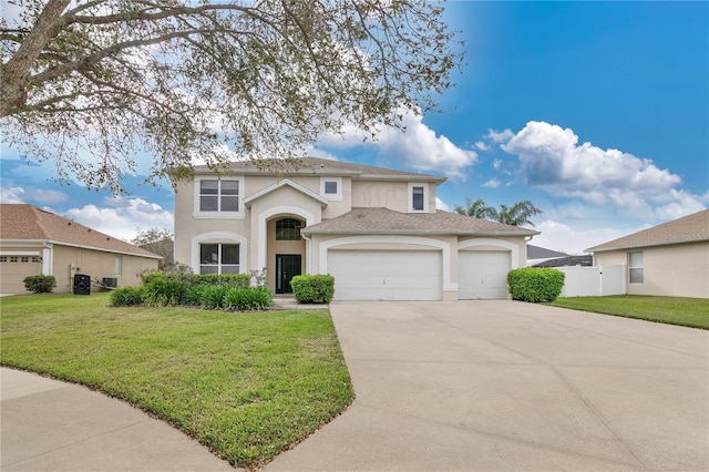 traditional home featuring a garage, driveway, stucco siding, fence, and a front yard