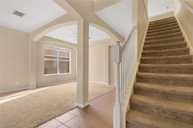 stairs with carpet flooring, visible vents, baseboards, and tile patterned floors