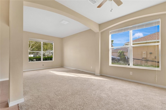 empty room featuring carpet floors, arched walkways, visible vents, and baseboards