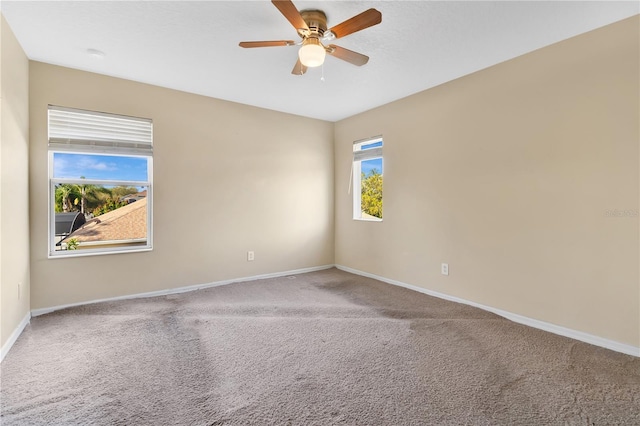 carpeted spare room with a ceiling fan and baseboards