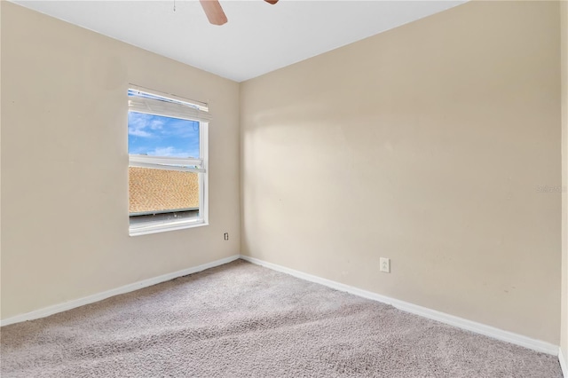 carpeted spare room with ceiling fan and baseboards