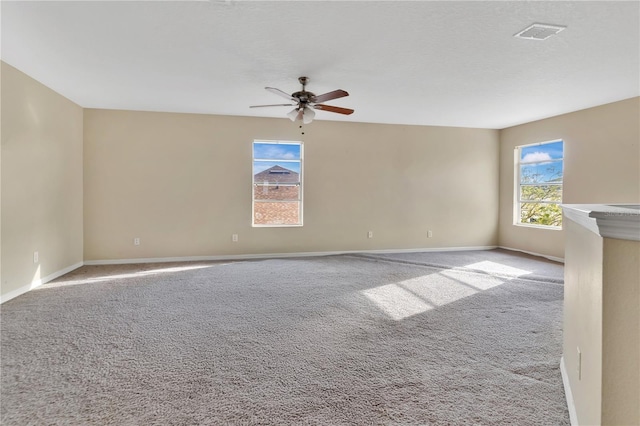 carpeted spare room featuring ceiling fan, a textured ceiling, visible vents, and baseboards