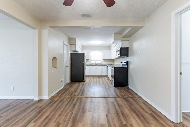 kitchen with visible vents, baseboards, stainless steel appliances, wood finished floors, and white cabinetry