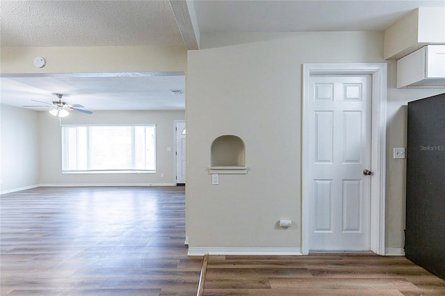 unfurnished room featuring a textured ceiling, a ceiling fan, baseboards, and wood finished floors