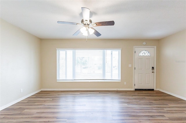 entryway with a ceiling fan, wood finished floors, baseboards, and a textured ceiling