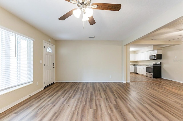 unfurnished living room featuring visible vents, light wood-type flooring, and baseboards