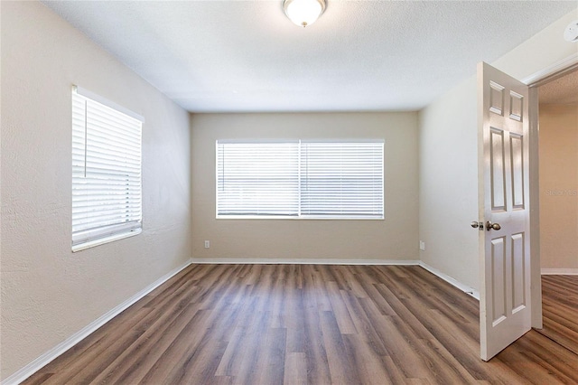 unfurnished room featuring a textured wall, a textured ceiling, baseboards, and wood finished floors