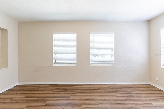 unfurnished room with baseboards and wood finished floors