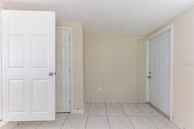 empty room featuring light tile patterned floors and baseboards