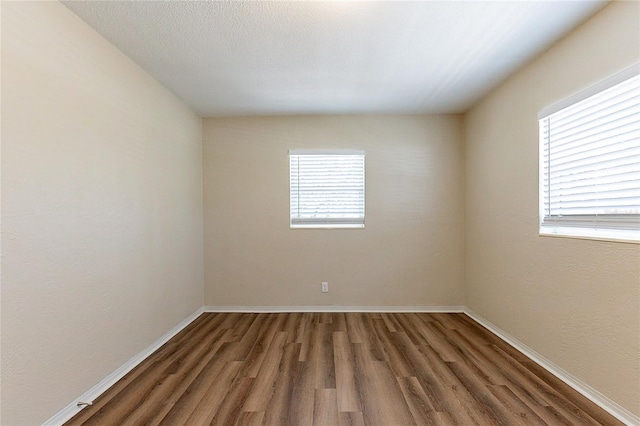 spare room with a textured ceiling, baseboards, and wood finished floors