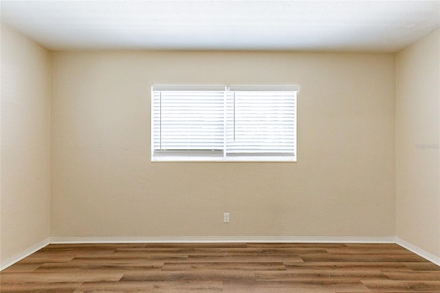 unfurnished room with baseboards and wood finished floors