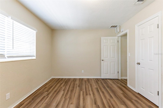 unfurnished room with visible vents, baseboards, and wood finished floors