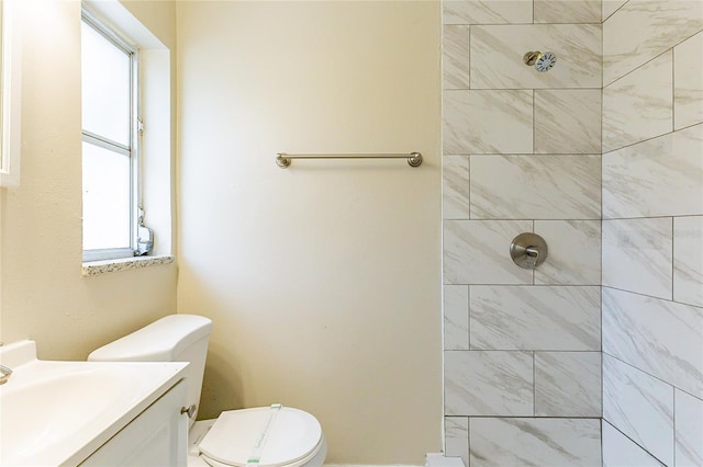 full bath featuring a tile shower, toilet, and vanity