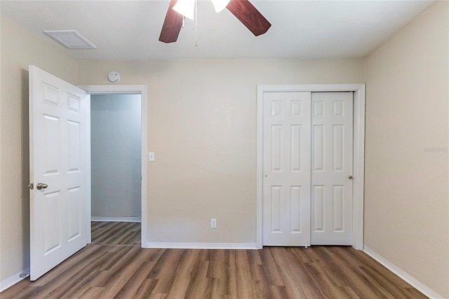 unfurnished bedroom with a closet, visible vents, baseboards, and wood finished floors