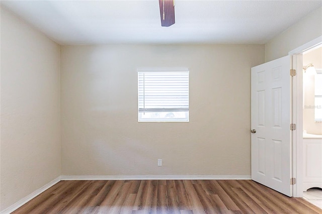 spare room featuring baseboards and wood finished floors