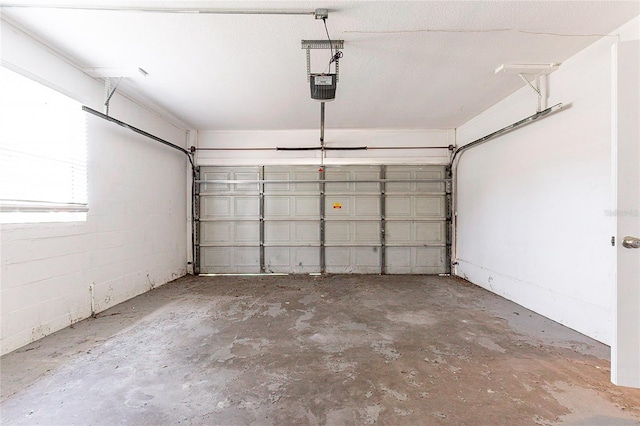 garage featuring concrete block wall and a garage door opener