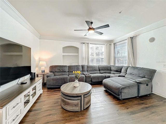 living room with ceiling fan, built in features, dark wood finished floors, and crown molding