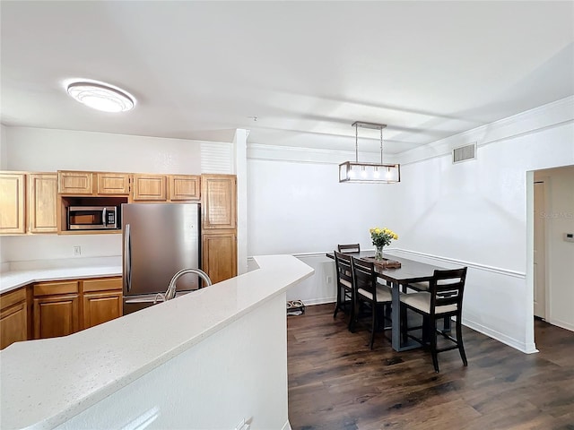 kitchen featuring visible vents, dark wood-style floors, appliances with stainless steel finishes, decorative light fixtures, and light countertops