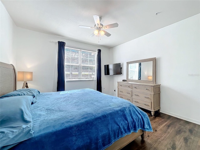 bedroom with dark wood-style floors, a ceiling fan, and baseboards