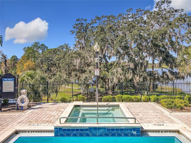 view of pool with a community hot tub and fence