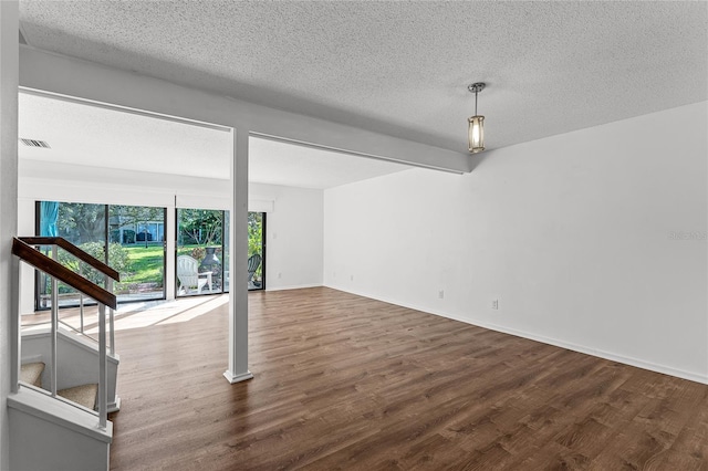 interior space featuring visible vents, a textured ceiling, baseboards, and wood finished floors