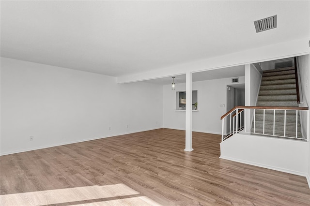 unfurnished living room with stairway, baseboards, visible vents, and wood finished floors