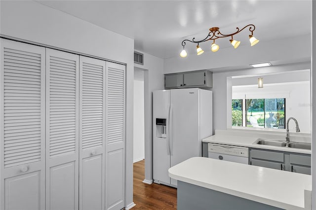 kitchen with white appliances, visible vents, dark wood finished floors, gray cabinetry, and a sink