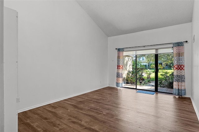 unfurnished room featuring baseboards, vaulted ceiling, and dark wood-style flooring