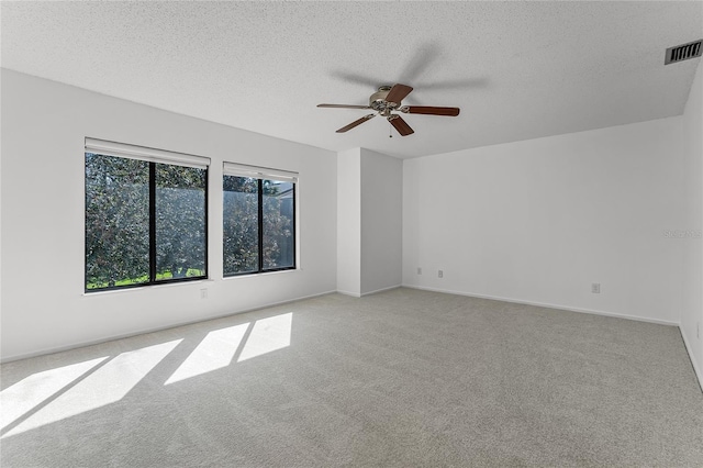 carpeted empty room with visible vents, ceiling fan, a textured ceiling, and baseboards