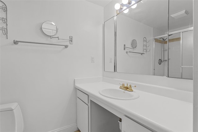 bathroom featuring visible vents, toilet, a shower with shower door, and vanity