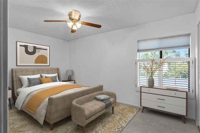 bedroom featuring light carpet, ceiling fan, baseboards, and a textured ceiling