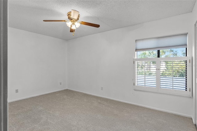 carpeted spare room featuring a textured ceiling, ceiling fan, and baseboards