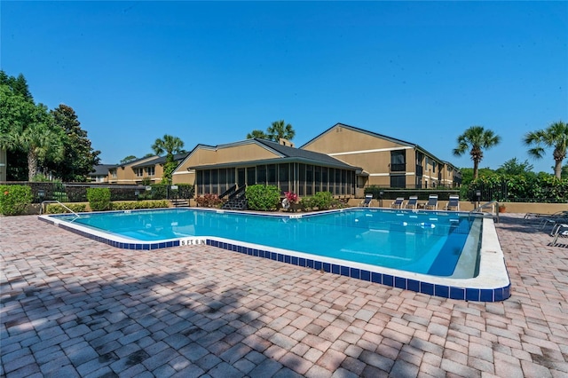 pool featuring a patio area, fence, and a sunroom