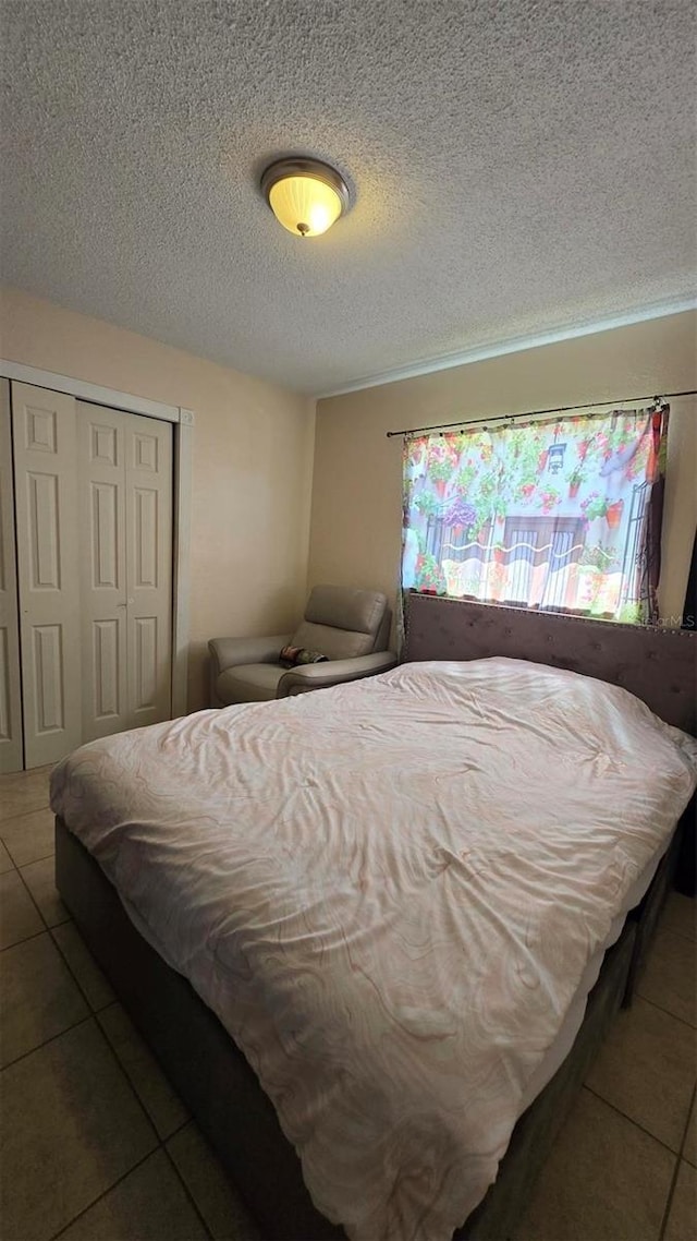 bedroom with a textured ceiling, a closet, and tile patterned floors