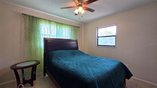 bedroom with a textured ceiling, tile patterned floors, a ceiling fan, and baseboards