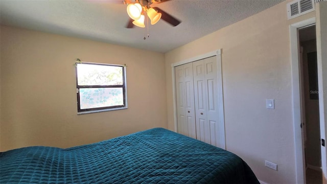 bedroom with a ceiling fan, a closet, visible vents, and a textured ceiling