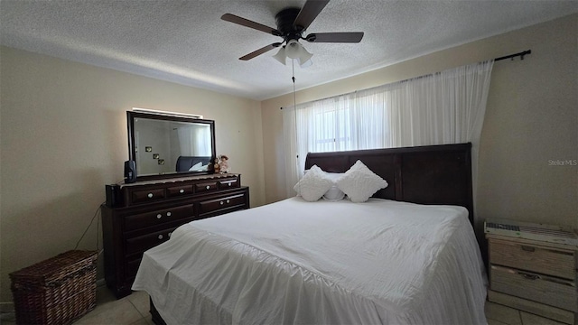 bedroom with a ceiling fan, tile patterned flooring, and a textured ceiling