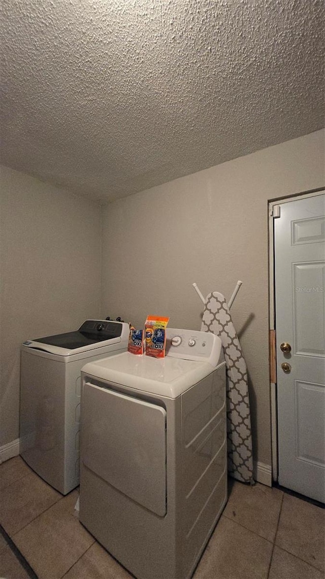 washroom with laundry area, light tile patterned floors, separate washer and dryer, and a textured ceiling