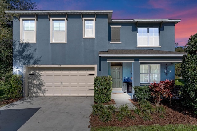 view of front of property with a garage, concrete driveway, a porch, and stucco siding