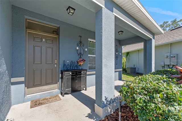 property entrance with central air condition unit, covered porch, and stucco siding